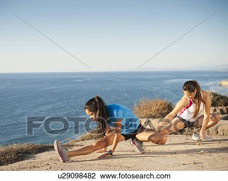 Stock Image - USA, California, San Diego, Two women stretching at sea coast. Fotosearch