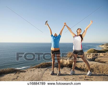 Stock Photo - USA, California, San Diego, Two women stretching at sea coast. Fotosearch