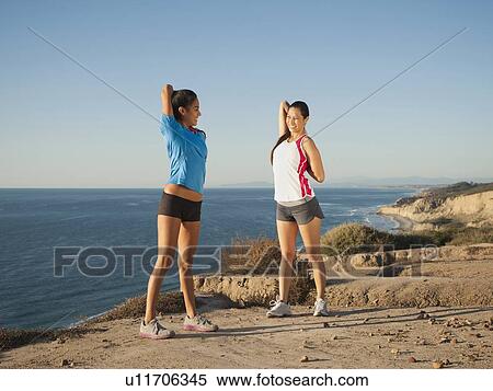 Stock Photography - USA, California, San Diego, Two women stretching on beach. Fotosearch