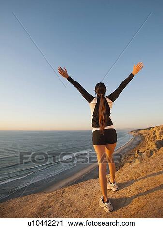 Stock Image - USA, California, San Diego, Woman stretching at beach. Fotosearch