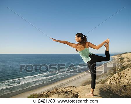 Stock Image - USA, California, San Diego, Woman practicing yoga on beach. Fotosearch