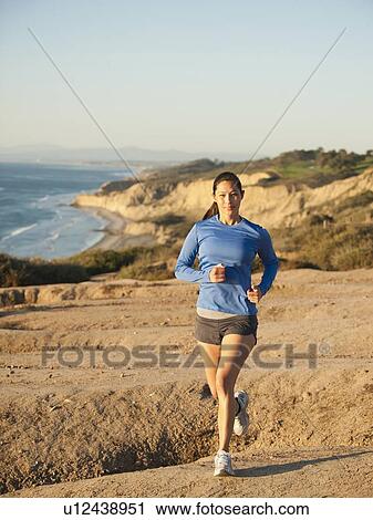 Stock Image - USA, California, San Diego, Woman jogging along sea coast. Fotosearch