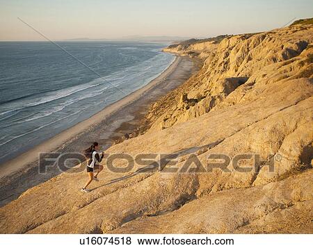 Stock Photo - USA, California, San Diego, Woman jogging along sea coast. Fotosearch