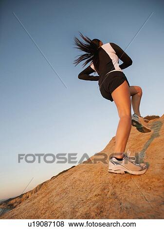Stock Photo - USA, California, San Diego, Woman running up rock. Fotosearch