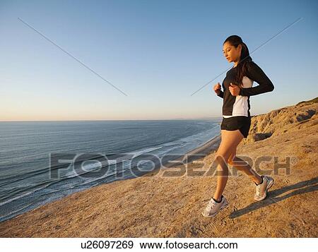 Stock Photo - USA, California, San Diego, Woman jogging along sea coast. Fotosearch