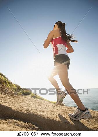 Stock Photo - USA, California, San Diego, Woman jogging along sea coast. Fotosearch