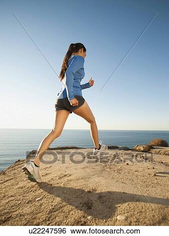 Stock Photograph - USA, California, San Diego, Woman jogging along sea coast. Fotosearch