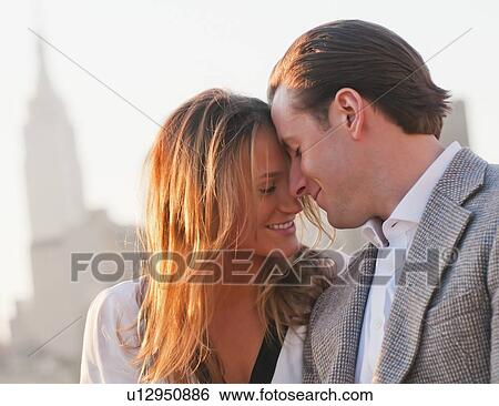 Stock Photograph - USA, New York, Long Island City, Close-up of happy young couple, Manhattan skyline in background. Fotosearch