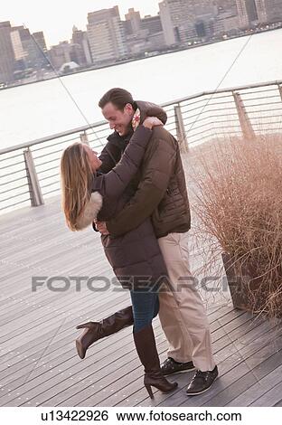 USA, New York, Long Island City, Young couple embracing on boardwalk View Large Photo Image Stock Photograph - USA, New York, Long Island City, Young couple embracing on boardwalk. Fotosearch