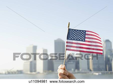 Stock Image - USA, New York State, New York City, Manhattan, Hand holding American flag. Fotosearch