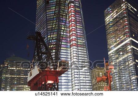 Stock Image - USA, New York State, New York City, crane in front of illuminated skyscrapers. Fotosearch