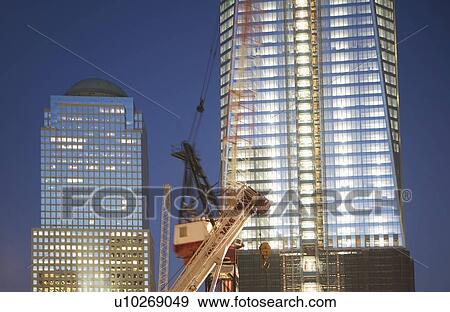 Stock Photo - USA, New York State, New York City, crane in front of illuminated skyscrapers. Fotosearch