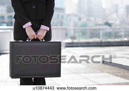 Stock Image - USA, Seattle, Midsection of businesswoman holding briefcase. Fotosearch