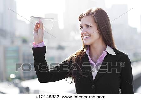 USA, Seattle, Smiling businesswoman holding paper plane View Large Photo Image Stock Photo - USA, Seattle, Smiling businesswoman holding paper plane. Fotosearch