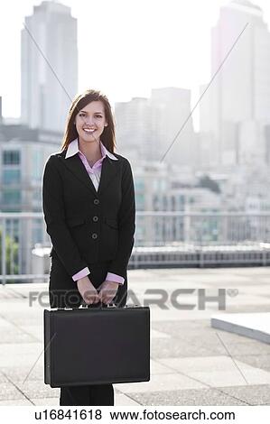 Stock Photo - USA, Seattle, Smiling young businesswoman holding briefcase. Fotosearch