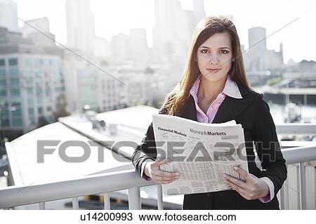 Stock Image - USA, Seattle, Young businesswoman reading newspaper. Fotosearch