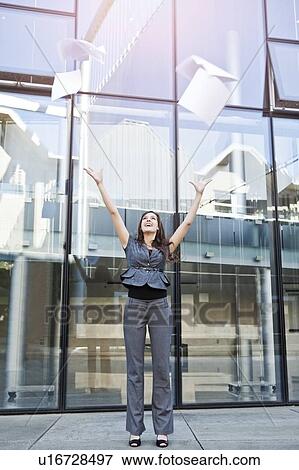 USA, Seattle, Young businesswoman throwing documents in front of office building View Large Photo Image Stock Photo - USA, Seattle, Young businesswoman throwing documents in front of office building. Fotosearch