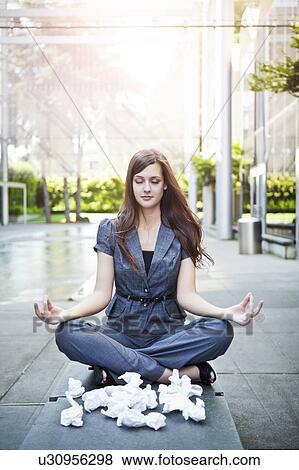 Stock Photo - USA, Seattle, Young businesswoman meditating in front of crumbled paper balls. Fotosearch