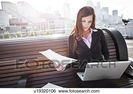USA, Seattle, Young businesswoman sitting on bench and working View Large Photo Image Stock Photograph - USA, Seattle, Young businesswoman sitting on bench and working. Fotosearch