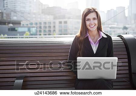 USA, Seattle, Young businesswoman working on laptop on bench View Large Photo Image Stock Photograph - USA, Seattle, Young businesswoman working on laptop on bench. Fotosearch