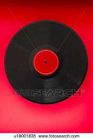 Stock Photography - Vinyl record in on red background, studio shot. Fotosearch