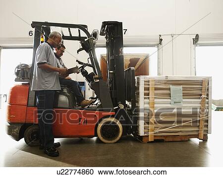 Warehouse workers talking by forklift truck View Large Photo Image Stock Image - Warehouse workers talking by forklift truck. Fotosearch