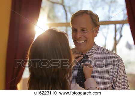 Stock Image - Woman helping man get dressed. Fotosearch