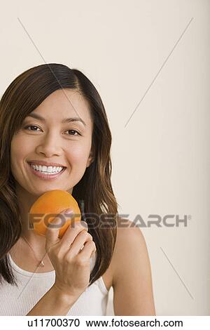 Stock Image - Woman holding orange. Fotosearch