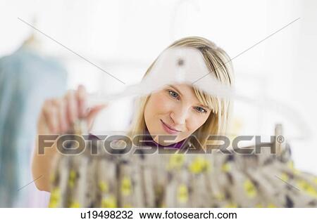 Stock Image - Woman looking at skirt in clothes store. Fotosearch