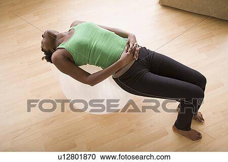 Stock Image - Woman lying on fitness ball. Fotosearch