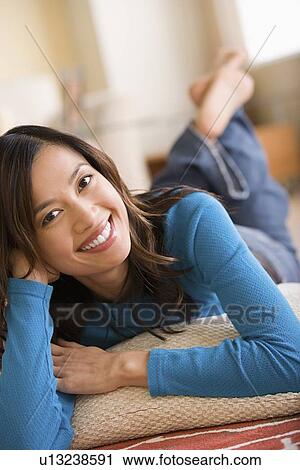Stock Image - Woman lying on floor at home. Fotosearch