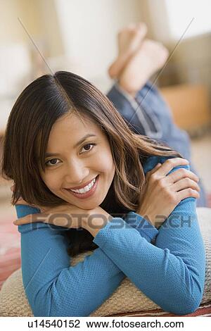 Stock Image - Woman lying on floor at home. Fotosearch