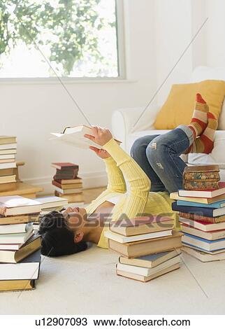 Stock Image - Woman reading among stacks of books. Fotosearch