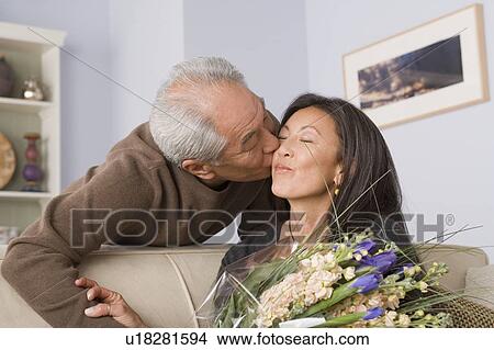 Woman receiving kiss and flowers from husband View Large Photo Image Picture - Woman receiving kiss and flowers from husband. Fotosearch