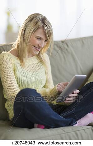 Woman sitting on sofa and using digital tablet View Large Photo Image Stock Image - Woman sitting on sofa and using digital tablet. Fotosearch