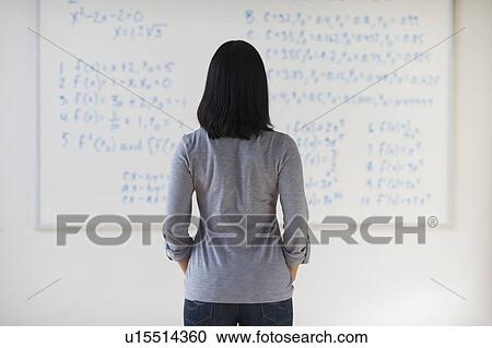 Stock Image - Woman standing in front of board with equations. Fotosearch