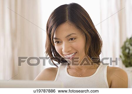 Woman using laptop and smiling View Large Photo Image Stock Photograph - Woman using laptop and smiling. Fotosearch
