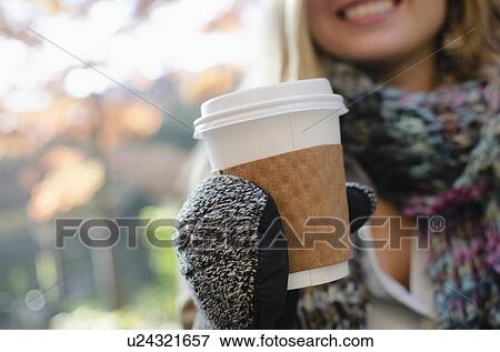 Stock Photo - Woman wearing gloves holding coffee cup. Fotosearch