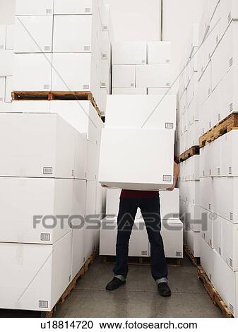 Stock Image - Worker carrying boxes in warehouse. Fotosearch
