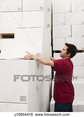 Stock Photograph - Worker stacking boxes in warehouse. Fotosearch