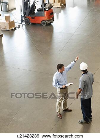 Stock Photograph - Workers talking in warehouse. Fotosearch