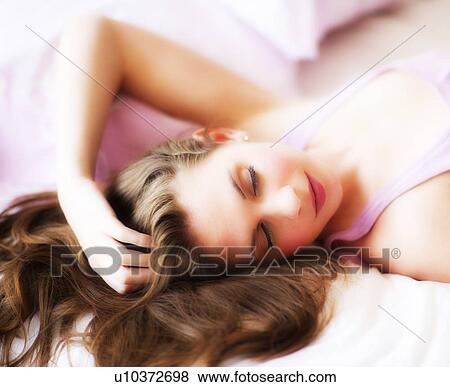 Stock Photo - Young attractive woman lying on bed. Fotosearch