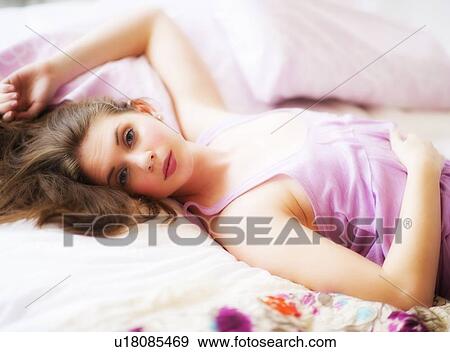 Stock Photo - Young attractive woman lying on bed. Fotosearch