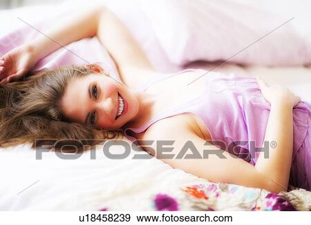 Young attractive woman lying on bed View Large Photo Image Stock Photo - Young attractive woman lying on bed. Fotosearch
