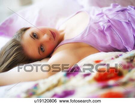 Stock Photograph - Young attractive woman lying on bed. Fotosearch