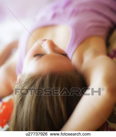 Stock Photograph - Young attractive woman lying on bed. Fotosearch