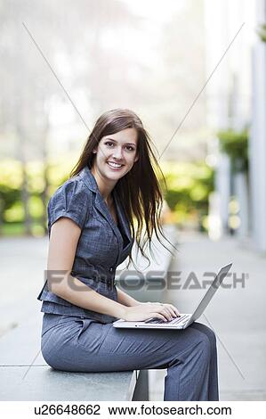 Young elegant woman sitting and using laptop View Large Photo Image Stock Image - Young elegant woman sitting and using laptop. Fotosearch