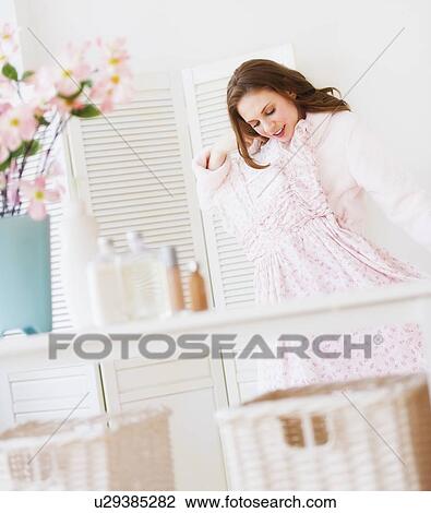 Young woman holding dress in bedroom View Large Photo Image Stock Image - Young woman holding dress in bedroom. Fotosearch