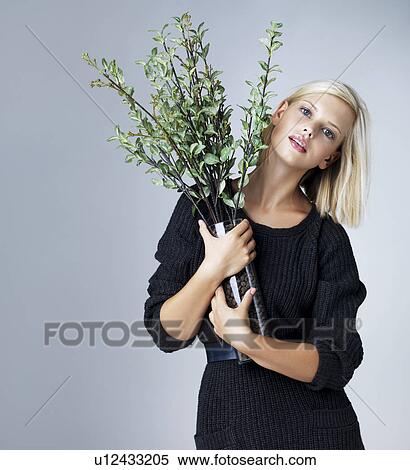 Young woman holding vase with green twigs, studio shot View Large Photo Image Stock Photography - Young woman holding vase with green twigs, studio shot. Fotosearch
