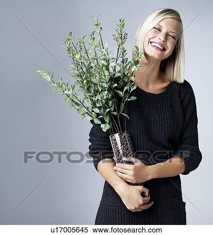 Young woman holding vase with green twigs, studio shot View Large Photo Image Stock Photography - Young woman holding vase with green twigs, studio shot. Fotosearch